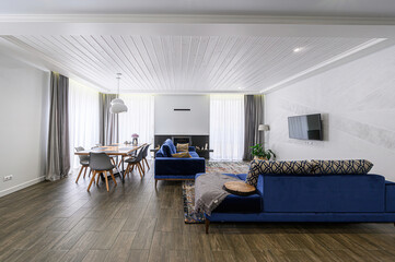 Bright living room with wood floors, blue sofas, dining table, and a modern fireplace
