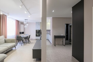 modern apartment interior featuring a living room, dining area, and glimpses of a kitchen. Neutral tones, sleek furniture, and soft lighting create a serene and stylish space
