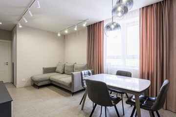 modern living room features a gray sectional sofa, a dining table with gray chairs, and stylish pendant lights. Large windows with pink curtains brighten the space