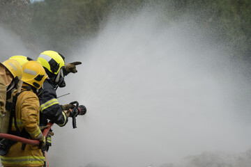 Firefighters are working together to put out the fire with water.