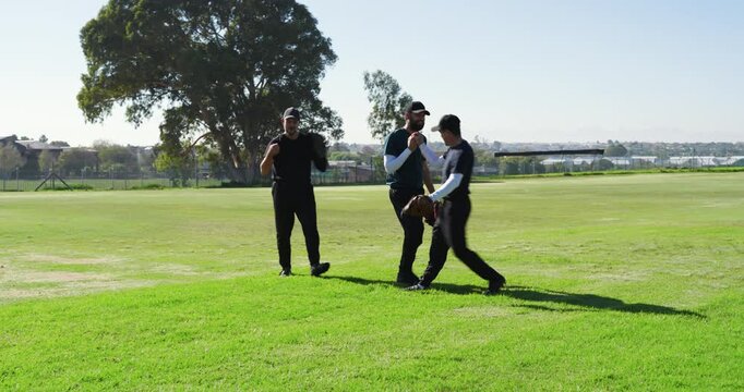 Following hand taps sparking male teammates warming up on ballfield tossing baseballs and rotating