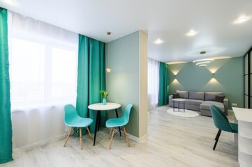 modern apartment interior featuring teal accents, a dining set by the window, and a comfortable living area with a gray sectional sofa