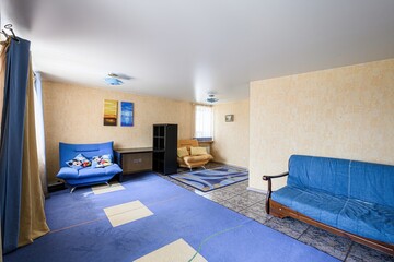 cozy room with blue sofas, textured walls, and mixed flooring of carpet and tile, creating a homey...