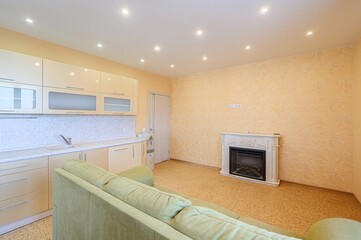 cozy apartment interior with a kitchen area, fireplace, and green sofa, bathed in warm, ambient light