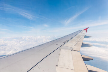 View from the airplane window at a beautiful cloudy sky and the airplane wing