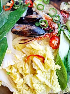 Making Korean seafood stew Haemultang  - Stew made of fish, blue crab, sea mussels, and fresh vegetables like Napa cabbage leaves,  big green oinon slices, green and red pepper slices, etc.