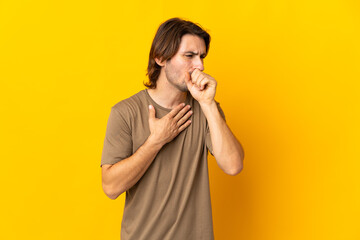 Young handsome man isolated on yellow background coughing a lot