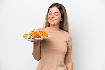 Young Rumanian woman holding waffles isolated on white background with happy expression