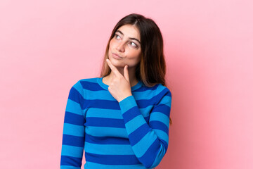 Fototapeta premium Young caucasian woman isolated on pink background having doubts