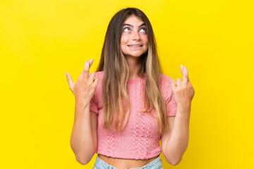 Young caucasian woman isolated on yellow background with fingers crossing and wishing the best
