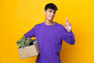 Man making a move while picking up a box full of things with fingers crossing and wishing the best