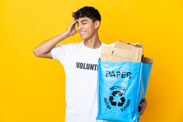 Man holding a recycling bag full of paper to recycle over isolated yellow background smiling a lot