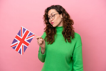 Young caucasian woman holding English flag isolated on pink background with sad expression