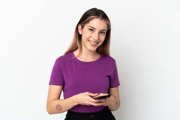 Naklejka premium Young caucasian woman isolated on white background sending a message with the mobile