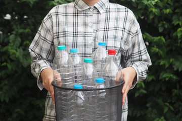 Woman hand holding bucket with plastic bottles for recycle. Reuse, Reduce, Recycle concept.