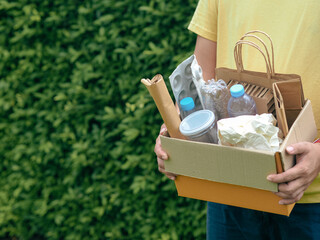 Young man hand holding box of garbage for recycling. Reuse reduce recycle concept.