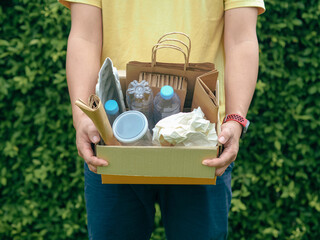 Young man hand holding box of garbage for recycling. Reuse reduce recycle concept.