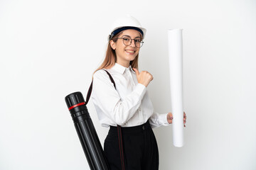Young architect woman with helmet and holding blueprints isolated on white background proud and...