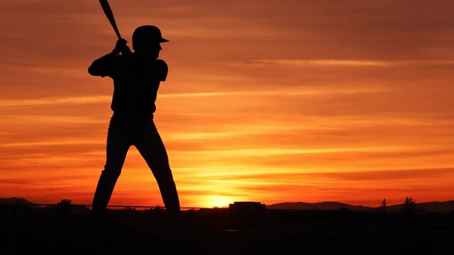 Baseball Silhouette at Sunset - The silhouette of a baseball batter is captured in a dynamic pose against a vibrant orange sunset.