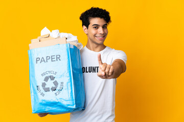 Young Venezuelan man holding a recycling bag full of paper to recycle showing and lifting a finger