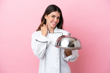 Young Italian chef woman holding tray with lid isolated on pink background laughing
