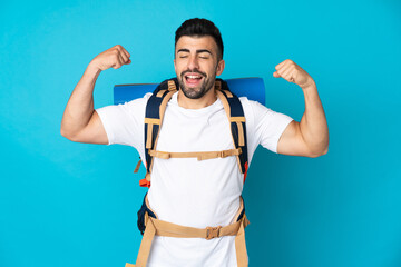 Young mountaineer man over isolated blue background doing strong gesture