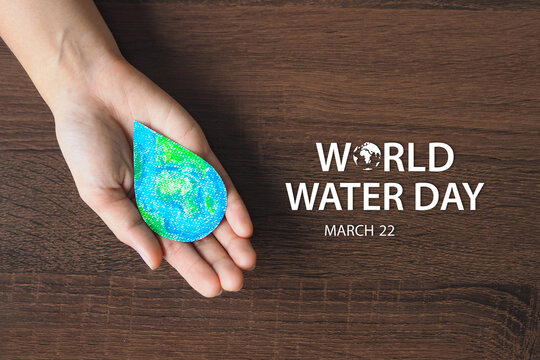 Woman hand holding earth in water drop on wooden background. World water day. Save water concept.