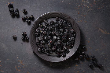 A plate of freshly picked blackberries on vintage surface.