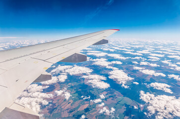 Fototapeta premium View from the airplane window at a beautiful cloudy sky and the airplane wing