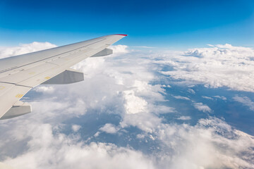 Obraz premium View from the airplane window at a beautiful cloudy sky and the airplane wing