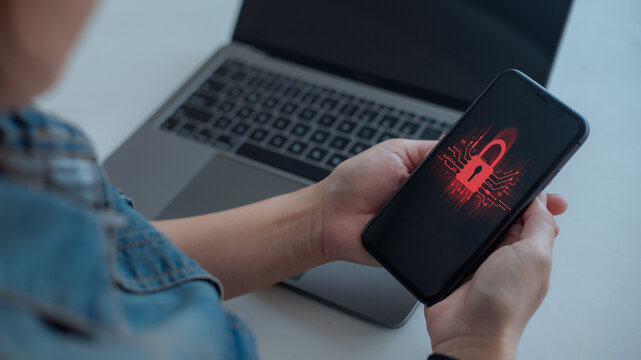 Person holding smartphone with red lock icon representing cybersecurity risk, data breach, hacking, and mobile security threat. Concept of online safety, IT risk, and data protection.