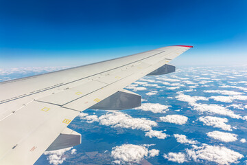 View from the airplane window at a beautiful cloudy sky and the airplane wing