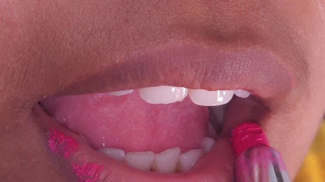 Macro lips. Professional makeup. Closeup of Indian teenage girl mouth with lipstick on lips. Beauty and makeup. Close up cosmetics for lips. Make up, applying lipstick, lips gloss on mouth. Beauty lip