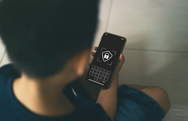 Back view of child holding smartphone with focus on screen showing lock icon and password keypad, online privacy, digital security and children's use of technology concept. overhead view