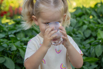 little girl drinking water on a nature background. Selective focus