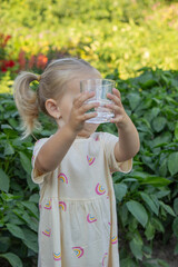 little girl drinking water on a nature background. Selective focus