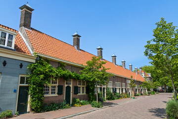 Historic Hofje in Delft, Netherlands, a picturesque row of traditional Dutch almshouses with charming facades and a tranquil, tree-lined street.