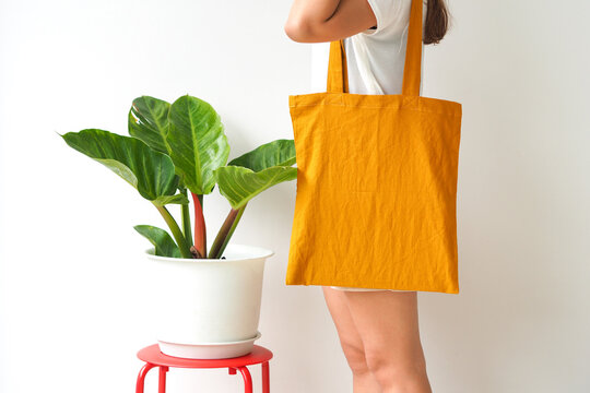 Woman holding canvas tote bag on white background. Reusable eco bag for shopping. Eco friendly concept. Mockup for design.