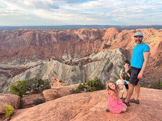 Father and children exploring rocky terrain at upheaval dome, canyonlands national park with scenic...