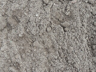 crumbly fresh fertile soil, slightly weathered, interspersed with dry grass blades, agricultural macro background, close view of farmland or arable land