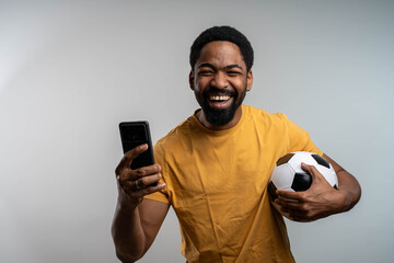 Excited man celebrating winning bet on smartphone watching soccer game isolated background