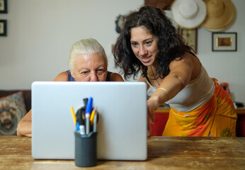 Computer class at home between mother and daughter. The two women are thirty-eight and seventy...