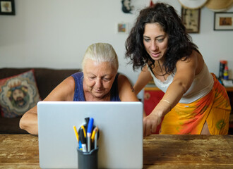 Computer class at home between mother and daughter. The two women are thirty-eight and seventy...