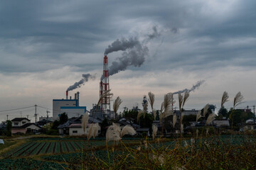Smoke is coming out of the factory's chimney on the outskirts of Yatsushiro City, Japan.