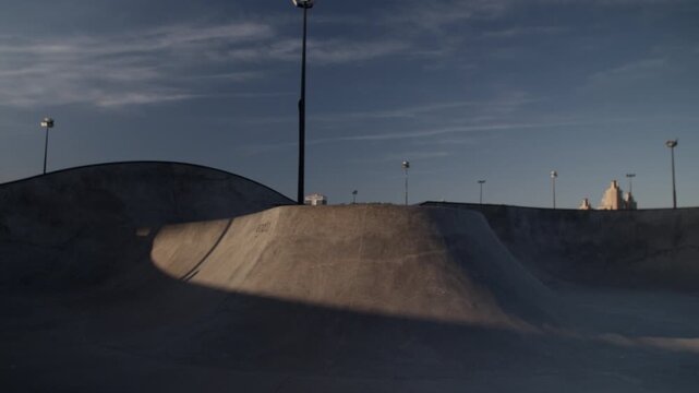 Fast roller skater jumps on ramp in extreme park at twilight 