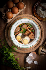 Brown boiled eggs with condiments in a bowl (braised eggs), rich broth, fragrant with herbs, a home-cooked Asian dish.