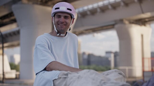 Happy roller skater in helmet rests sitting on sports ground