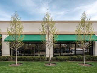 Commercial Building Facade with Green Awnings and Landscaped Lawn in Spring.