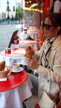 Stylish woman in trench coat enjoying breakfast at Parisian cafe terrace