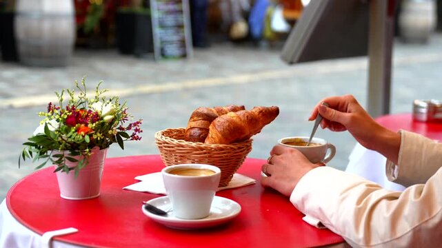 Parisian breakfast with croissants coffee and flowers on red cafe table